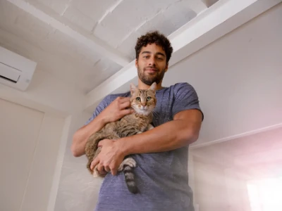 Młody mężczyzna w pomieszczeniu, trzymający na rękach kota
