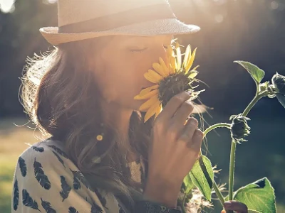 Kobieta stoi na polu i wącha słonecznik
