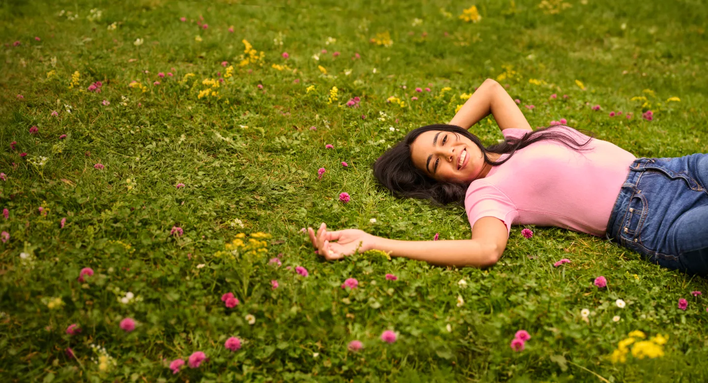 Woman relaxing in a field of flowers, carefree and free from allergy symptoms.